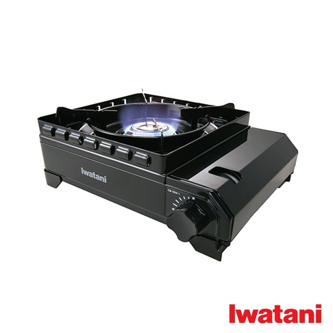 黑色金屬材質的卡式爐，爐火呈現藍色火焰，爐體側面有「Iwatani」品牌標誌，並設有黑色旋鈕和刻度盤。