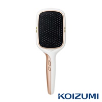 白色的手持式離子養髮梳，梳頭部分有黑色梳齒，邊緣鑲有玫瑰金飾邊，握柄處有玫瑰金點綴，底部有KOIZUMI品牌標誌