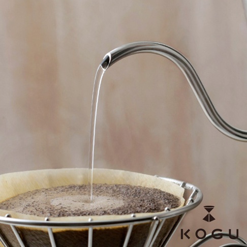 日製 18-8 不鏽鋼極細口咖啡手沖壺，細長壺嘴優雅彎曲，正在將水流精準地注入盛有咖啡粉的濾紙中。