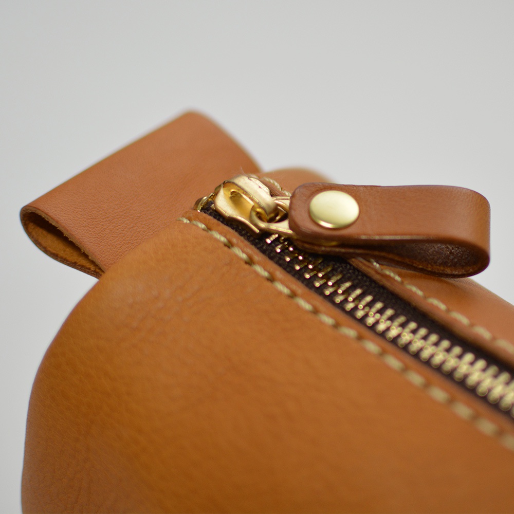 職人手作皮革多用途收納筆袋 KP-146，特寫金色拉鍊與皮革拉環，縫線細緻，皮革呈現自然光澤，顏色為溫潤的棕褐色。