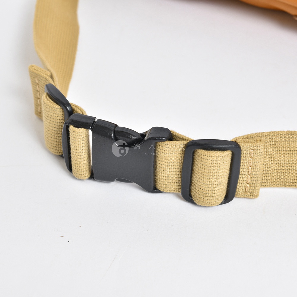 帆布材質的米色織帶，配有黑色塑膠插扣和調節環，用於固定背包。