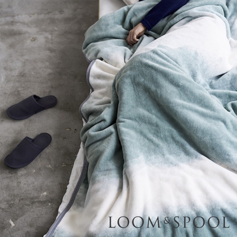 抗菌短絨舒柔單人毯，採用漸層藍綠色與白色設計，材質柔軟，搭配一雙深藍色拖鞋。