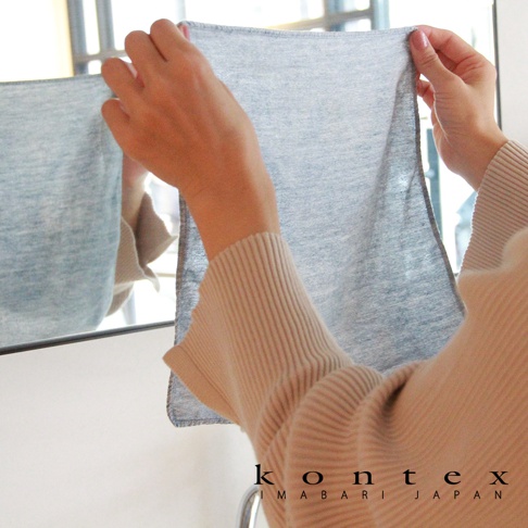 雙手拿著一塊淺藍色的薄款棉麻拭巾，材質輕柔，邊緣有細緻的縫線。