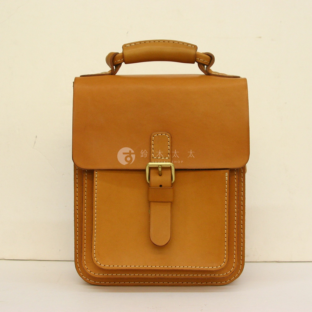 職人手作皮革單肩兩用小方包，淺棕色，方形包身，頂部提把，前蓋有皮帶扣設計，車縫線明顯。