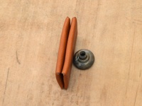 棕色皮革製成的雙開卡片收納夾，緊閉著，旁邊有一個金屬鈕扣。