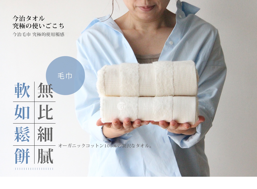 兩條米白色有機棉製成的雙織毛巾，織有鬆餅紋，由一位身穿淺藍色襯衫的人士雙手捧著。