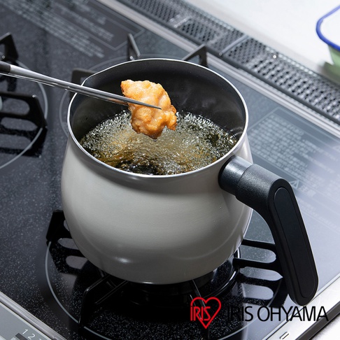 淺灰色鑽石不沾單柄小湯鍋，鍋內裝有熱油，夾著一塊炸物準備放入油中。鍋柄為黑色，整體材質看起來為金屬。