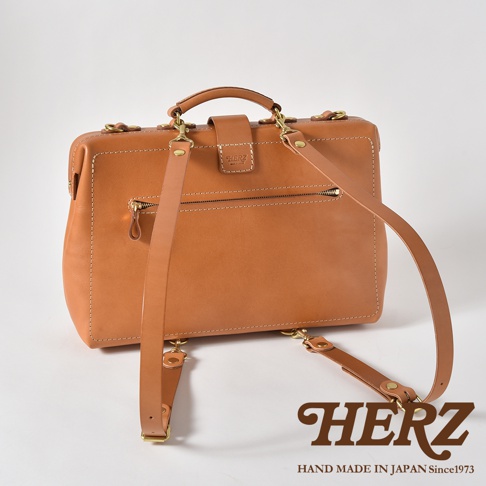 棕色皮革製成的職人手作三用包，帶有拉鍊前袋、頂部提把、可拆卸肩帶和復古金屬扣。