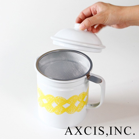 白色琺瑯濾油壺，壺身上印有黃色編織紋樣，配有可拆卸的濾網及白色壺蓋，手柄處有金屬連接。