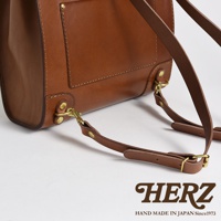 職人手作皮革復古口金後背包，採用棕色皮革製成，搭配黃銅色金屬扣環和可調節的皮革背帶，展現經典復古風格。