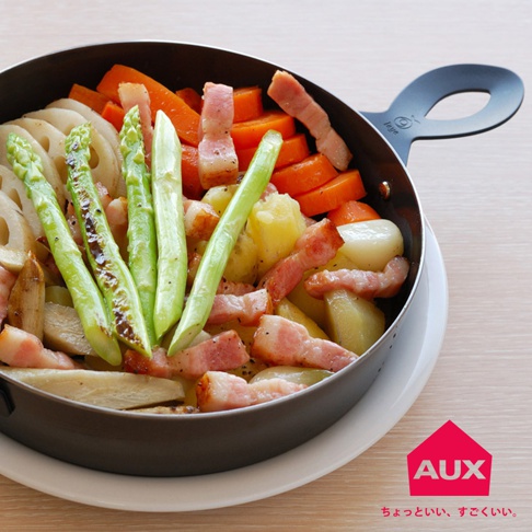 leye 附蓋小烤鍋裝有煮熟的蘆筍、胡蘿蔔、馬鈴薯塊、蓮藕片和培根。鍋子是黑色金屬材質，帶有黑色手柄。