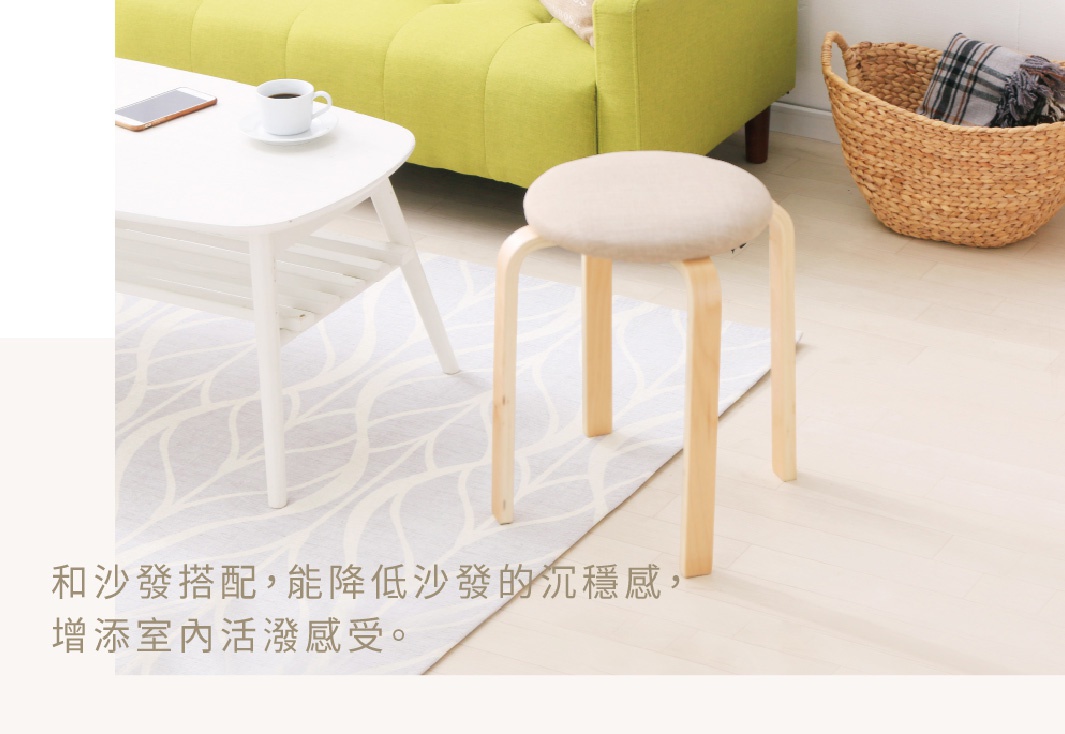 一張木質圓椅凳，椅面為淺米色布料，椅腳為彎曲的淺木色木質結構，共四支椅腳，椅凳放置在地板上，旁邊有白色茶几、綠色沙發和編織籃。