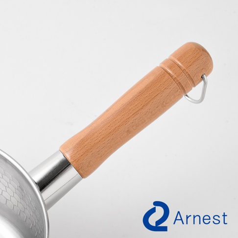 Arnest品牌的燕三條不鏽鋼雪平鍋手柄特寫，呈現圓潤的淺色木質握柄，連接處採用金屬材質，末端附有銀色金屬掛環，鍋身表面帶有細緻的蜂巢狀紋理。