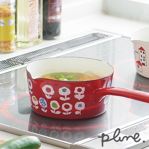 紅色琺瑯單柄牛奶鍋，鍋身印有白色花朵圖案，鍋內裝有湯品，放置於電磁爐上。
