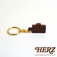 職人手作皮革相機造型鑰匙圈，深棕色皮革製成，搭配金色金屬鑰匙圈與扣環。