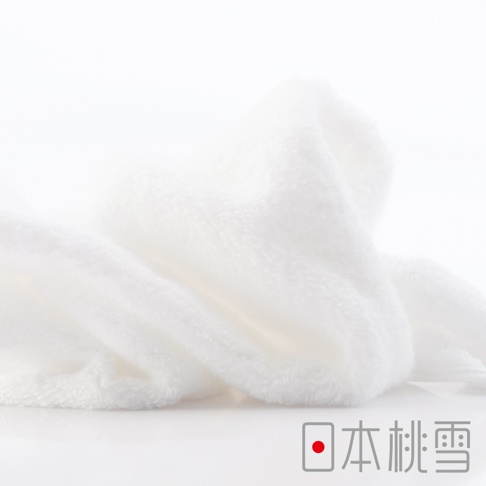 一條柔軟的白色超長棉方巾，質地蓬鬆，有細緻的毛圈，角落帶有「日本桃雪」的標誌。