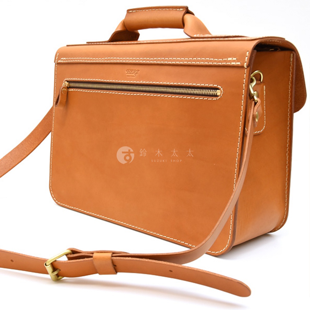棕色皮革製作的雙扣兩用單肩包，有頂部提把和可調式肩帶，正面有拉鍊口袋，縫線細緻。