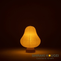 一個黃色紙質燈罩的迷你裝飾提燈，燈罩呈現梨形，由橫向的紙條編織而成，底部為木質基座，散發溫暖的光線。