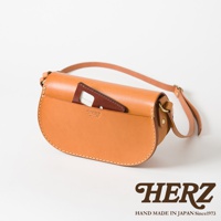 職人手作皮革迷你馬鞍包，採用天然皮革製成，呈現溫潤的棕褐色。包包為半月形設計，設有方便取放物品的前袋，內有品牌標誌。可調節長度的肩帶，適合斜挎或肩背。