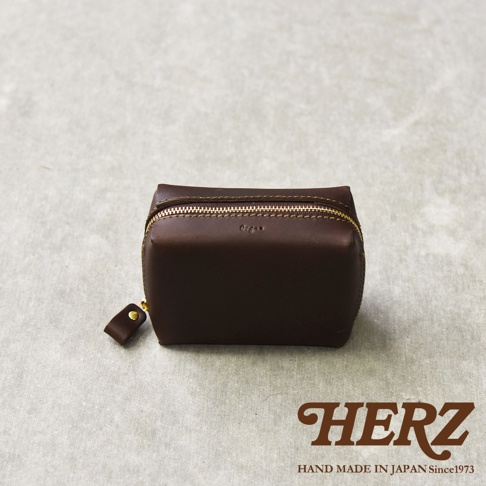 職人手作的咖啡色皮質Organ箱型收納包，有金屬拉鍊和皮革拉環，下方印有HERZ字樣與HAND MADE IN JAPAN Since1973。