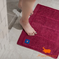 深紅色竹棉混紡厚感浴墊，帶有織紋和壓紋，角落有藍色標籤和橘色河馬圖案。