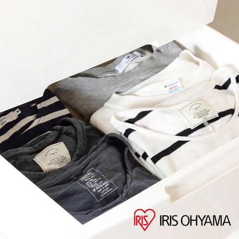 白色抽屜內收納著幾件衣物，包含深藍與白色條紋上衣、一件灰色長袖上衣、一件白色長袖上衣，以及一件炭灰色短袖上衣。