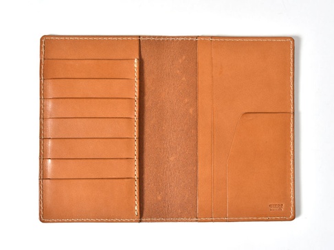 職人手作皮革多用途收納長夾，天然皮革材質，經典棕色調。內部設計有六個卡片夾層，左側為開放式插槽，右側為兩個較深的收納袋。整體以米色車線縫製，質感細膩。