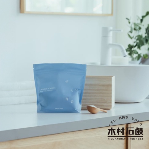 藍色包裝袋裝有 ASUNO 無香料溫和中性洗衣粉，袋上印有白色字母 asuno 及 LAUNDRY POWDER 字樣。旁邊有木製盒子和一個裝有白色粉末的木勺。