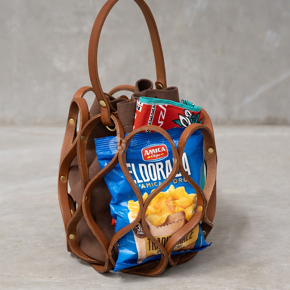 日本HERZ職人手作皮革Organ編織水桶包，棕色皮革編織外框內搭麂皮內袋，包內裝有一包AMICA CHIPS ELDORADO洋芋片與印花布料