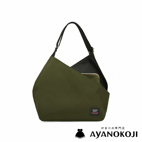 掛著黑色背帶的綠色單肩包，包包採梯形設計，底部寬而向上收窄，包包正面有一個方形的品牌標籤。