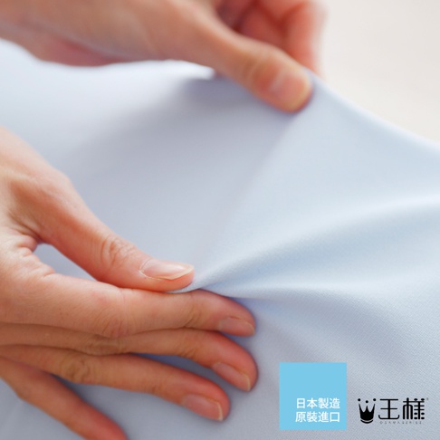 雙手拉扯淺藍色細緻光滑的布料，展示其柔軟與彈性。布料表面紋理細膩，質感輕薄。
