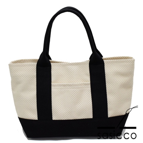 米白色刺子織迷你托特包，配有黑色提把和底部，正面有一個米白色刺子織外袋。