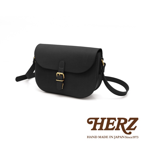 黑色皮革經典馬鞍包，設有金色搭扣和可調式肩帶，展現簡約優雅設計。