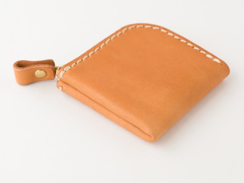 棕褐色皮革製成的手工零錢包，菱形設計，配有小巧的皮革拉環和黃銅扣，邊緣以白色車線縫製。