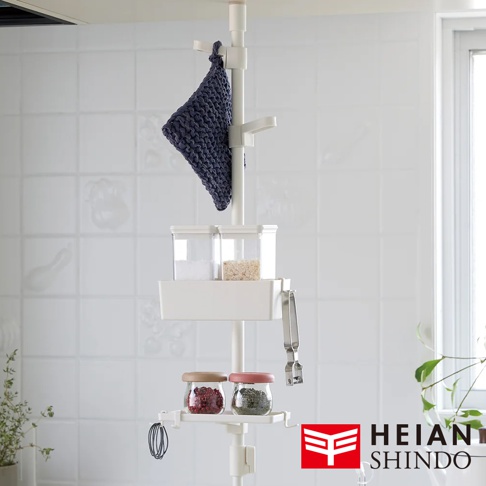 白色直撐架上掛有深藍色布料，架上層有兩個透明儲物盒，下方有白色收納籃，籃旁掛著金屬夾。下層有兩個玻璃罐，分別裝有紅色和綠色顆粒狀物品，架子底部有掛勾。