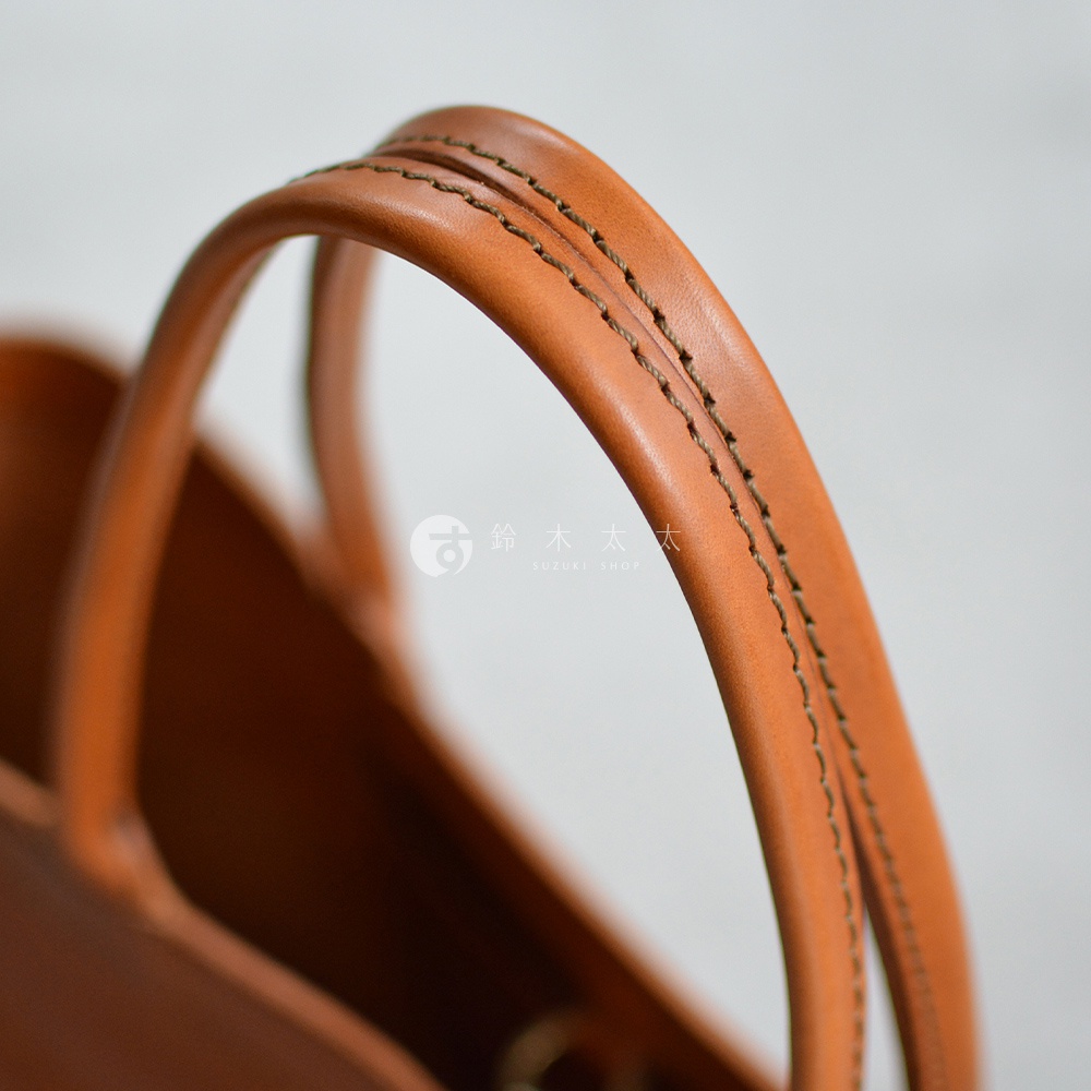 職人手作皮革包的提把特寫，展現精緻縫線與溫潤的皮革質感