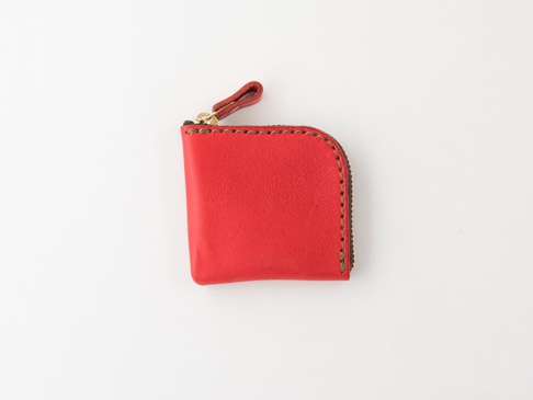 紅色皮革製成的手工零錢包，有拉鍊開合和皮革拉環，縫線清晰。