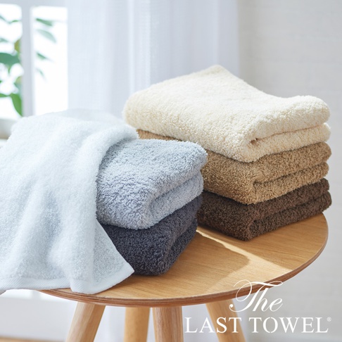 The LAST TOWEL 魔法瞬吸純棉柔浴巾，展示了堆疊的純棉毛巾，顏色有淺藍、淺灰、深灰、米白、淺褐和深褐。