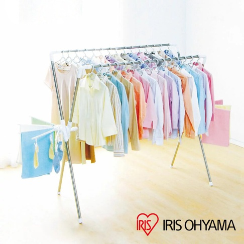 不鏽鋼X型曬衣架，架上掛滿各式顏色鮮豔的衣物，有淺黃、粉紅、藍色、紫色等，衣架下方有小型的側翼，上面掛著毛巾和襪子，整體為銀色和白色。