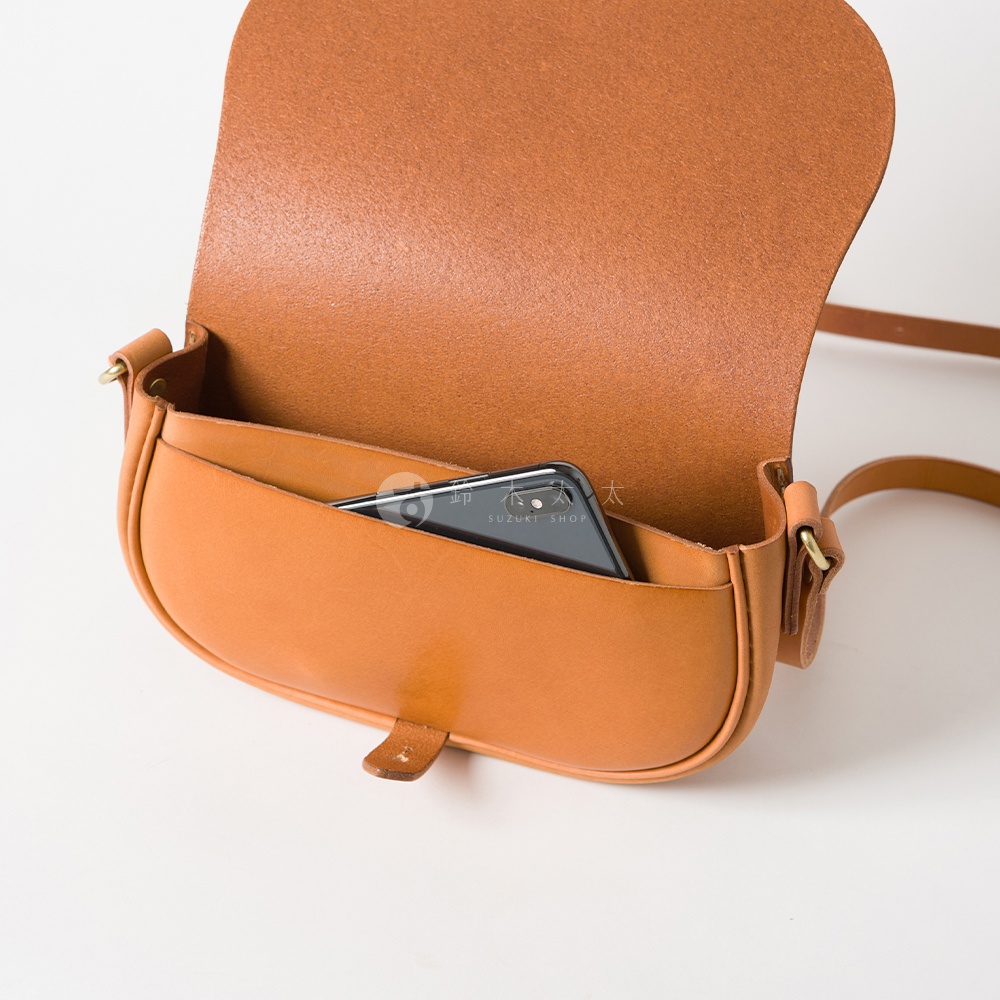 職人手作皮革迷你馬鞍包，經典棕色，採用真皮材質，包身呈現圓潤馬鞍形狀，掀蓋設計，內袋可放入手機。
