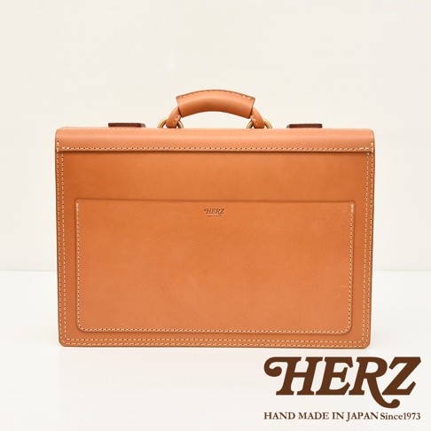 職人手作皮革機師箱 BC-31，採用 tan 色天然皮革，箱體結構方正，正面設有同色系皮革外袋，側邊與箱蓋邊緣皆以米色車線縫製，箱頂配有皮革提把及金屬扣環。