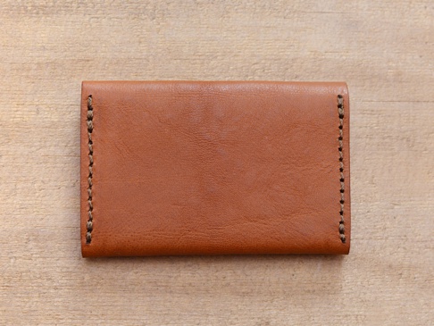 職人手作皮革Organ薄型名片短夾 (GS-49)，呈現溫潤的棕褐色皮革，邊緣有工整的手縫車線，整體造型簡約，適合收納名片。