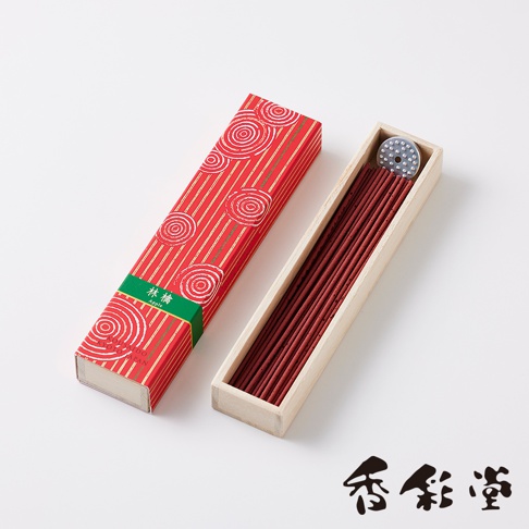京都百樂香白檀香氛線香，紅色包裝盒飾有金色螺旋圖案與條紋，內含一盒深棕色香氛線香，一旁另有一個裝有香氛線香的淺色木盒，盒蓋上帶有金屬香座。