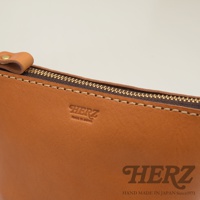 職人手作皮革三角收納包 KF-1，展示棕褐色皮革材質，帶有金色拉鍊和標誌性燙金壓紋。