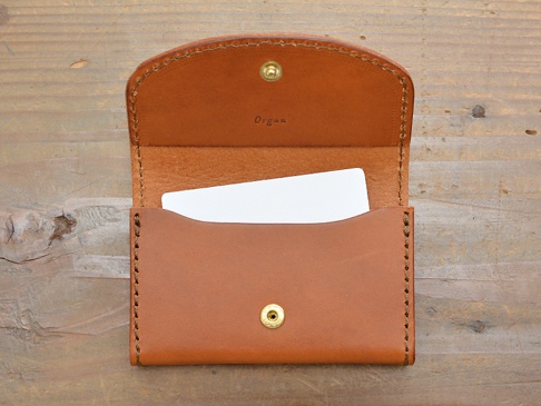職人手作皮革Organ商務用名片夾，經典棕色，翻蓋設計，內含白色名片，材質為真皮，邊緣車縫線整齊。