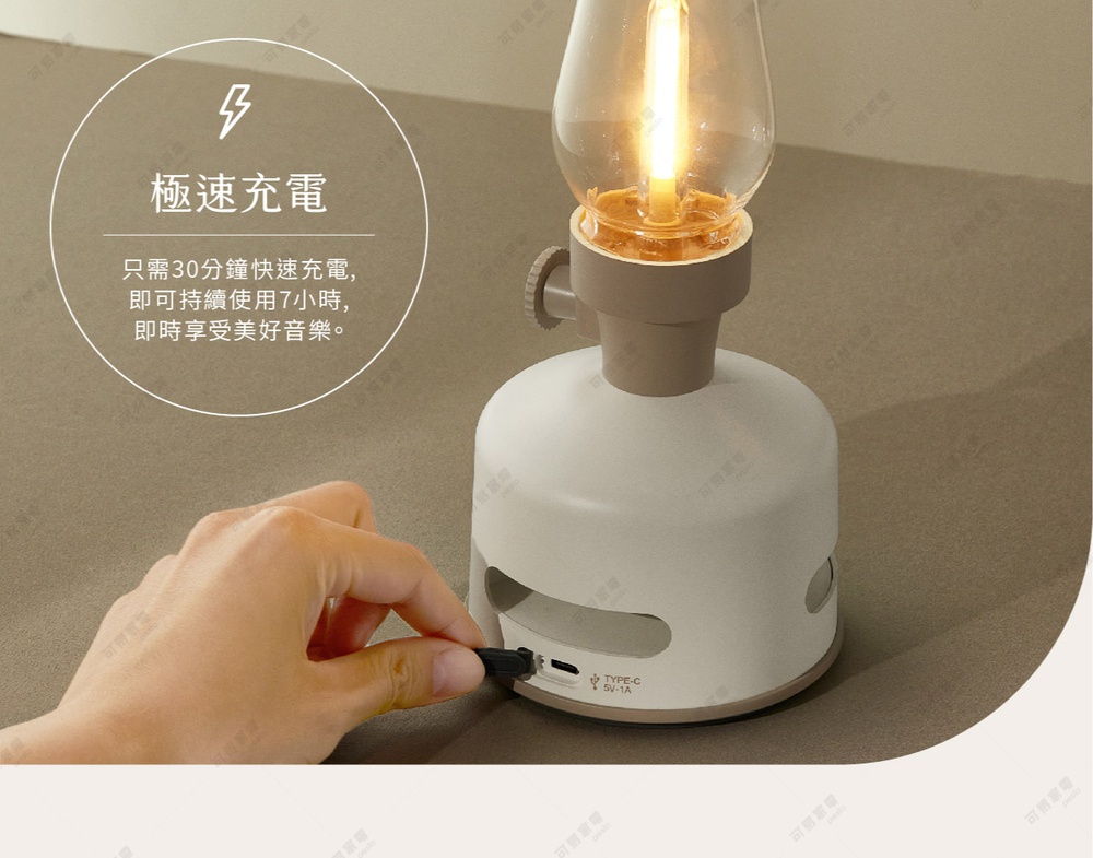白色煤油燈造型藍牙音響，配有透明燈罩和燈泡，下方為圓形底座，設有充電孔，一隻手正在插入 Type-C 充電線。