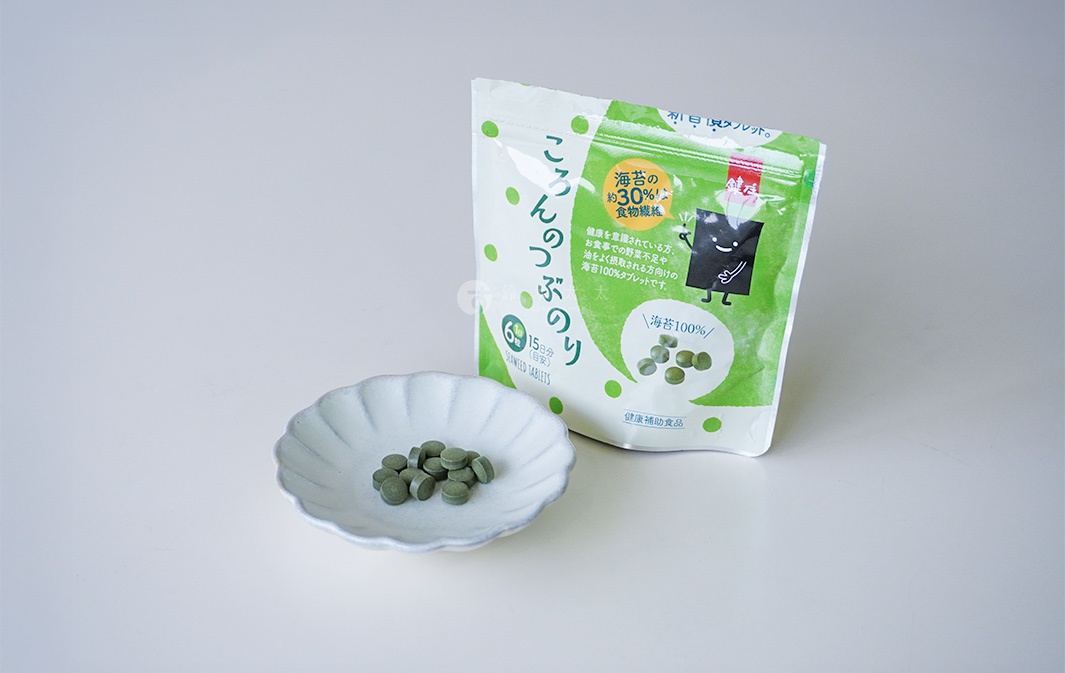 一包綠色包裝的鍵庄超微粉海苔錠，旁邊有一個淺色貝殼狀小盤，盤內放有數顆綠色海苔錠。