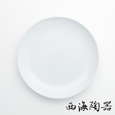 一個白色的波佐見燒 Common 陶瓷料理盤，直徑 24 公分，盤面光滑，邊緣略有弧度，底部有黑色書法字樣「西海陶器」。