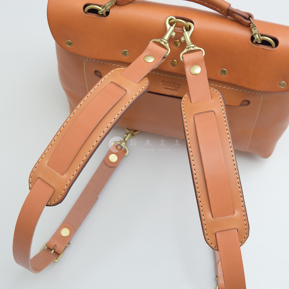 職人手作皮革肩墊，採用真皮材質，顏色為淺棕色，帶有精緻縫線與金屬扣環，設計簡約實用。