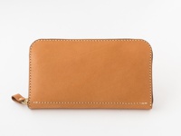 職人手作皮革大容量拉鍊長夾，採用天然棕色皮革製成，觸感溫潤，車縫線整齊細緻，配有金色金屬拉鍊及同色系皮革拉頭，設計簡約實用，展現皮革的自然紋理與質感。